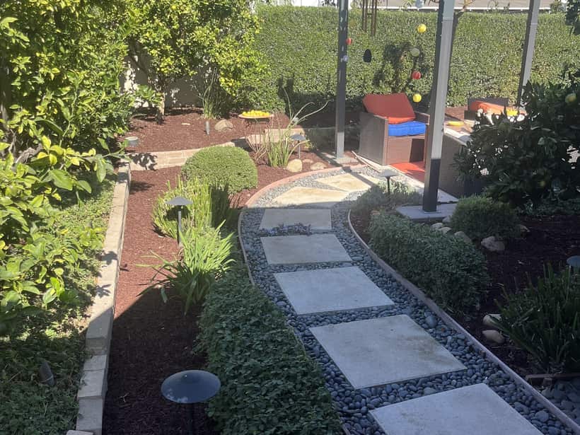 Paver walkway set in pebble between planted beds in a backyard in the Anaheim area