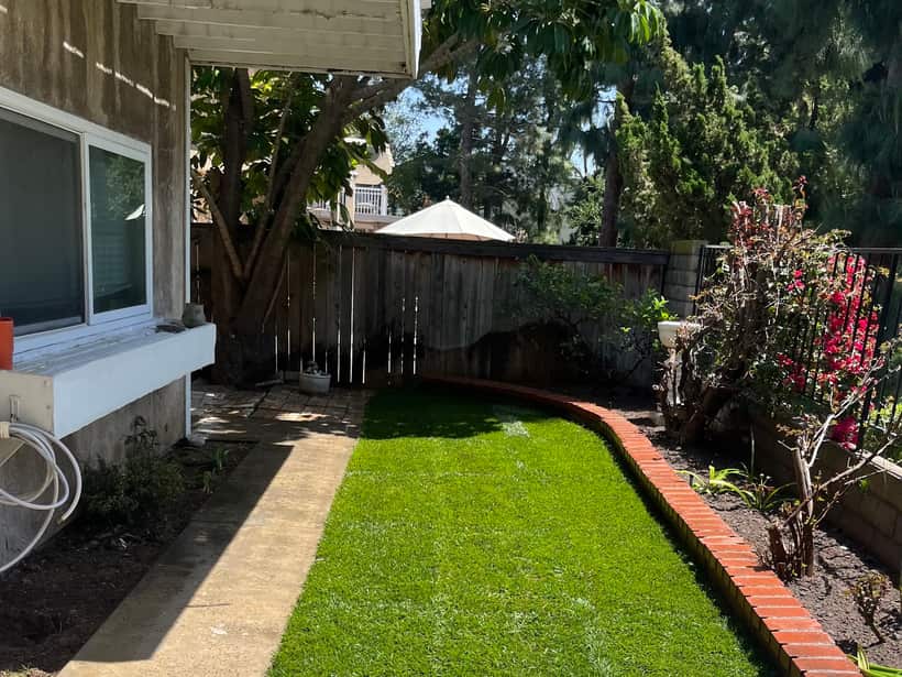 Narrow side yard finished in artificial turf with a brick edge, in the Anaheim area